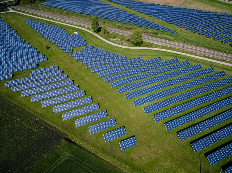 Aerial view of a utility-scale solar farm beside a railway