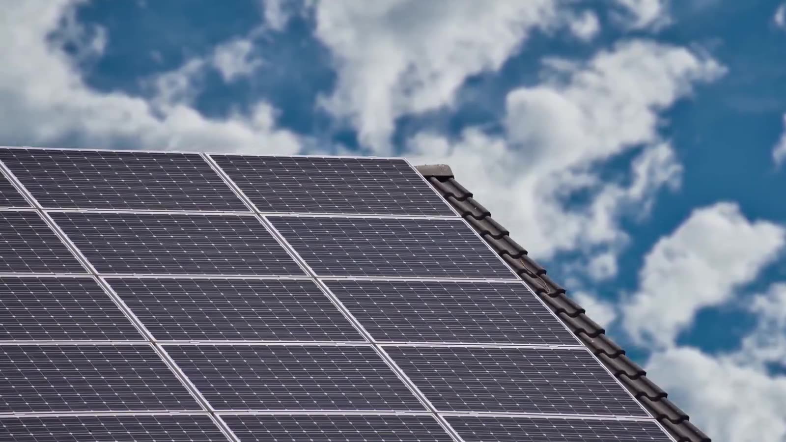 Solar panels angled toward a bright, cloud-scattered sky